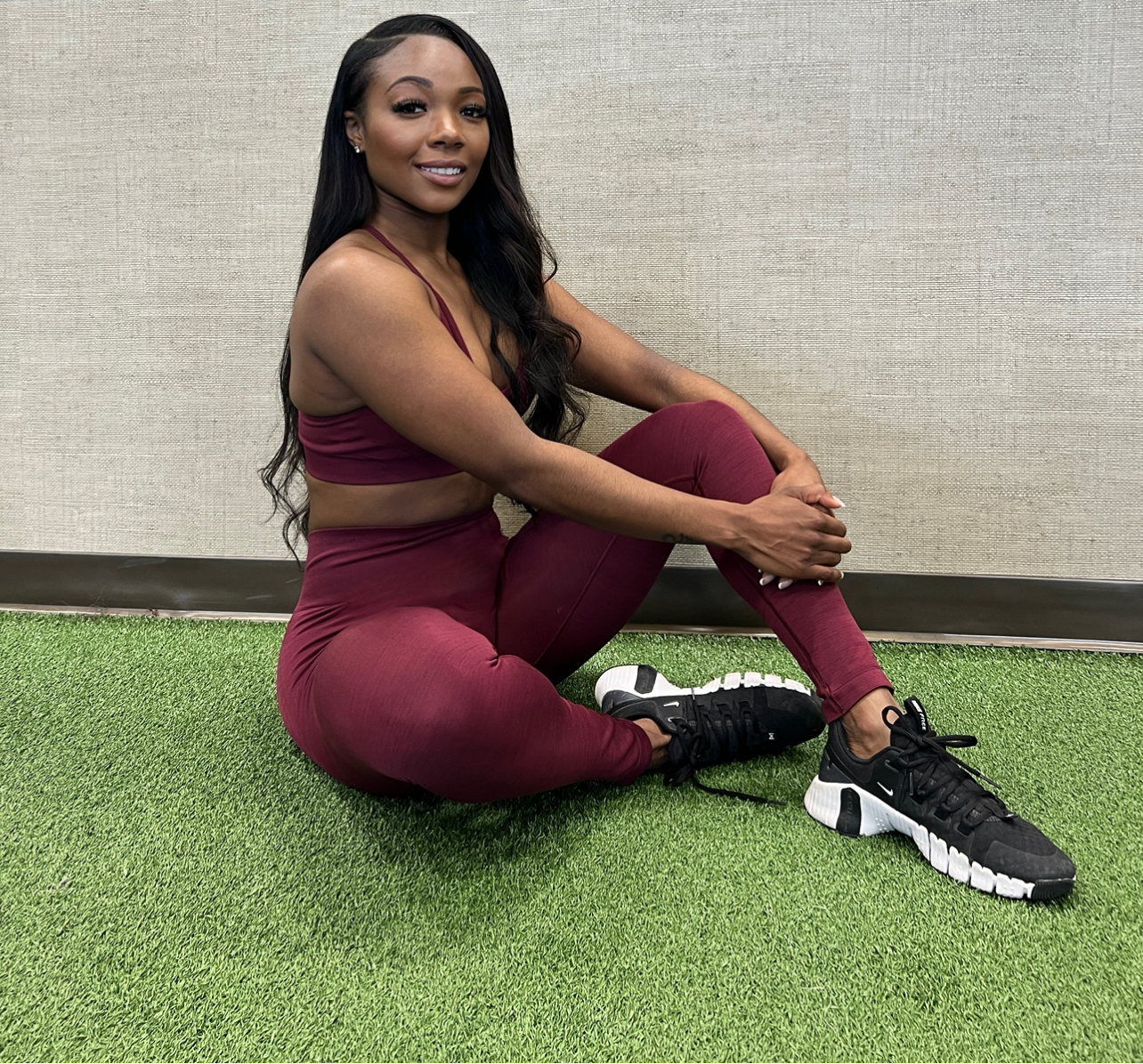 Coach posing for the camera while seated on the ground, dressed in athletic attire.
